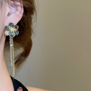 Detailed close-up of crystal flower earrings with long gold chain tassels and blue petals