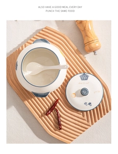 Top view of a ceramic lard pot with lid and spoon on a rustic wooden tray