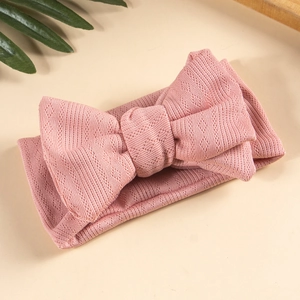 Detail of a pink knit baby headband featuring a double-layer jacquard bow with texture