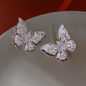 Macro shot of silver butterfly earrings with sparkling cubic zirconia on a gray surface