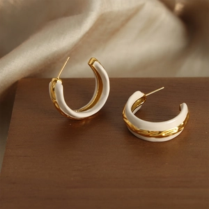 Vintage style gold-plated C-shape enamel hoop earrings with woven texture on wooden base