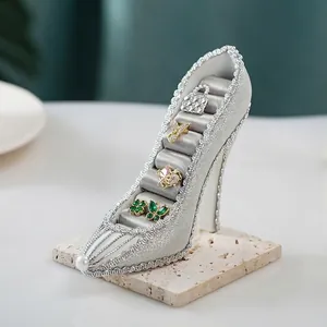Macro shot of silver glitter high heel jewelry stand with gray velvet ring slots