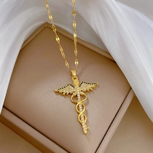 Elegant gold-plated caduceus pendant necklace with crystals on a jewelry display box