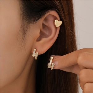 Close-up of gold lightning bolt earrings with zircons and a heart ear cuff on model