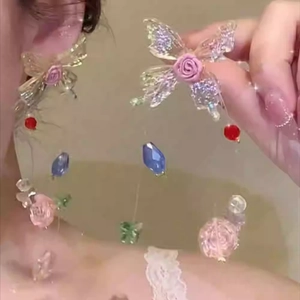 Close-up of handmade floral butterfly drop earrings with colorful beads and rose detail