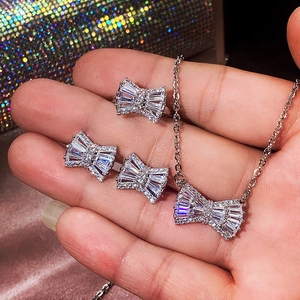 Strikvormige sieradenset met zilveren ketting, oorbellen en ring tegen een glanzende tas