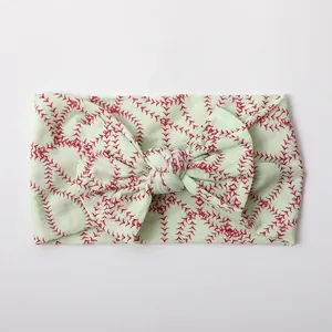 Detail of soft pale green nylon baby headband with baseball stitch print and bow knot