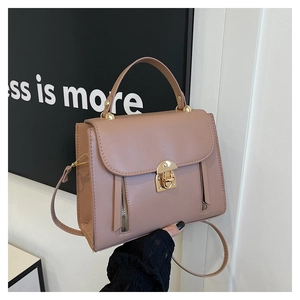 Detail of dusty rose leather handbag with metal twist lock and dual side zippers