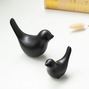 Minimalist black ceramic bird statues on white table with golden books decor