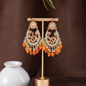Bohemian dangle earrings with gold tassels and orange beads on a vintage display