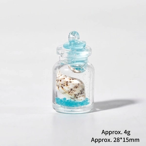 Détail d'une mini bouteille avec sable bleu et coquillage, dimensions de 28x15mm environ