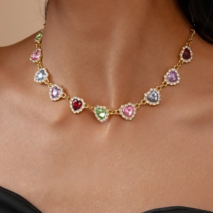 Gros plan d'un collier de luxe en or avec des gemmes colorées en cœur porté par un mannequin