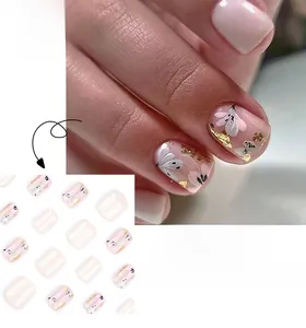 Detail of short square press-on nails with white flowers, gold foil, and pink gradient