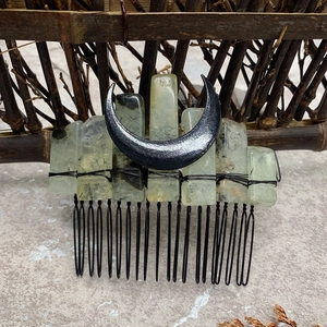 Detailed close-up of natural green stones and black moon crescent on a metal hair comb