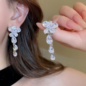 Dettaglio degli orecchini a farfalla con nappe in zircone indossati da una modella