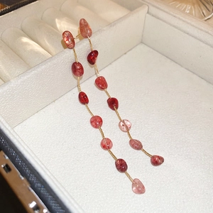 Detail view of long tassel earrings with strawberry quartz stones and golden chains