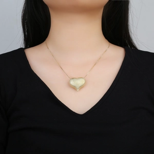 Elegant gold-plated heart pendant necklace with frosted finish on a female model