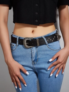 Detail of vintage black leather belt featuring star studs and carved silver metal buckle