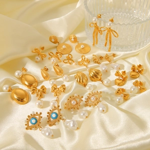 Elegant 18K gold-plated bow and pearl earrings set on silk fabric with evil eye details