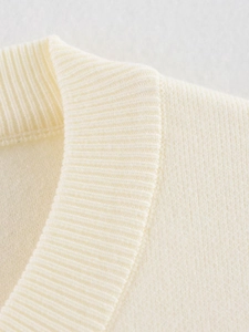 Primer plano del escote de la chaqueta de punto crema con textura acanalada y tejido suave