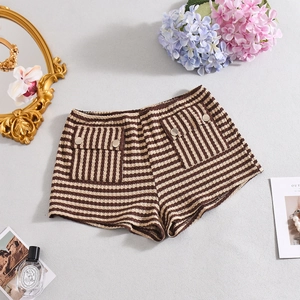 Gedetailleerd beeld van gestreepte gebreide shorts met metalen knopen en decoratie