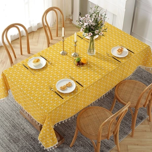 Top view of yellow geometric cotton linen tablecloth with tassel edges on a dining table