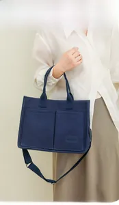 Close-up of a navy canvas tote bag featuring double front pockets and adjustable strap