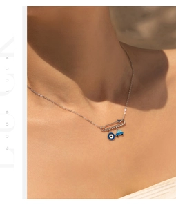 Detail view of silver safety pin necklace with blue evil eye and car charms