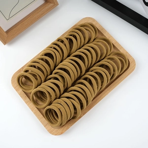 Detail of khaki elastic thick hair ties neatly arranged on a natural wooden tray