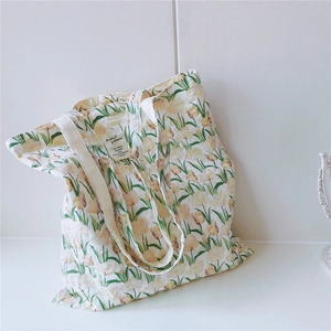 Detailaufnahme der gelben Tulpenprints und des Stoffetiketts auf der weißen Baumwolltasche