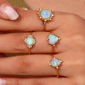 Close-up of 18K gold plated opal rings in sun, heart, and teardrop shapes on finger