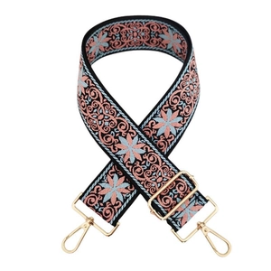 Détail de la bandoulière en jacquard brodé avec motifs floraux et mousquetons dorés