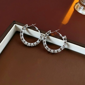 Macro shot of silver hoop earrings with clear rhinestones in a brown jewelry box