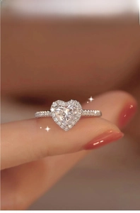 Macro shot of a S925 silver heart moissanite ring with halo diamonds on a finger