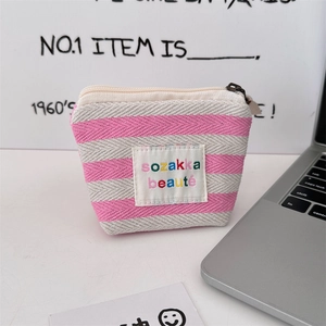 Detail of pink and grey knitted stripe makeup bag with metallic zipper and fabric tag