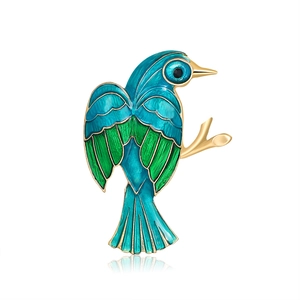 Exquisite blue and green enamel bird brooch with golden metal branch on white background