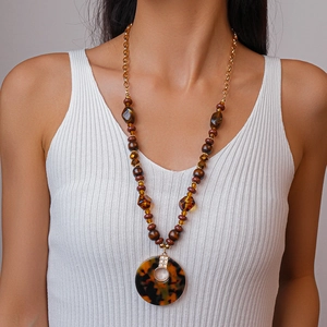 Gros plan d'un collier de perles vintage avec perles en acrylique ambré et pendentif