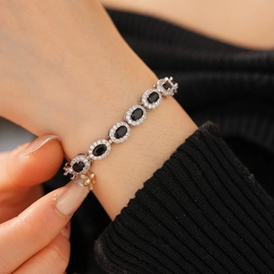 Macro detail of silver adjustable bracelet featuring oval black stones and halo crystals