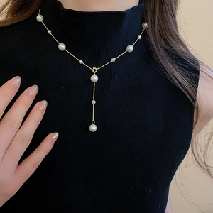 Elegant Y-shaped gold pearl necklace layered on a black turtleneck sweater for women