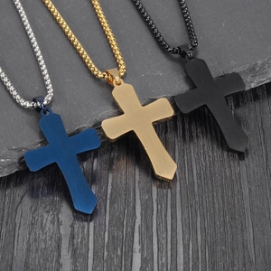 Detailed view of blue, gold, and black titanium steel cross pendants on stone slabs
