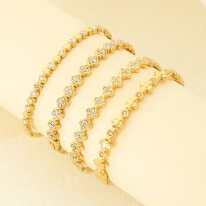 Set of four gold-plated bangle bracelets featuring clover and star charms with zircons