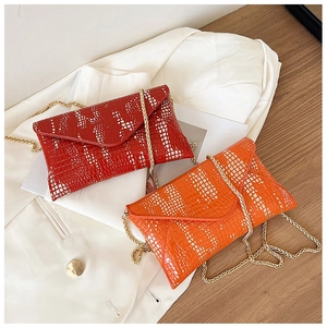 Detail view of red and orange crocodile pattern envelope bags on a white blazer