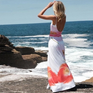 Detail of a floral maxi dress with backless design against a coastal beach background