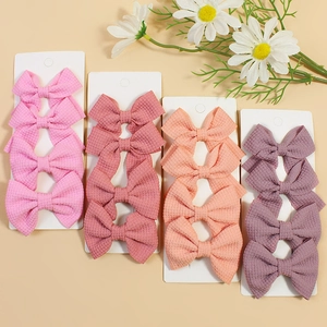 Flat lay of colorful waffle texture bow hair clips set with floral decor on warm beige background