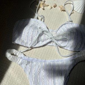 Detailaufnahme der weißen strukturierten Seersucker-Bikinistoff mit Muscheldekoration