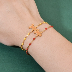 Set of two gingerbread man stainless steel bead bracelets for women on a dark green background