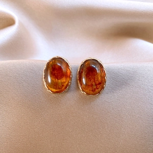 Close-up of vintage gold twisted earrings with oval amber-toned tiger eye stones