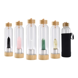 Set of glass water bottles with natural bamboo lids and colorful healing crystal columns