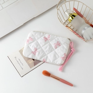 Detail of white quilted floral cosmetic bag with pink bow print and woven wristlet