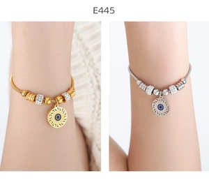 Detail of gold and silver snake bone bracelets with blue evil eye charms and crystal beads